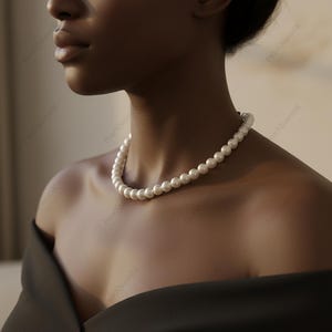 May include: A strand of white pearls, forming a necklace. The pearls are evenly sized and have a soft sheen. The necklace is worn around the neck, offering a classic and sophisticated appearance. The pearls are approximately 0.8 cm in diameter.