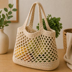 Puede incluir: Un bolso tote beige tejido a ganchillo con dos asas, lleno de productos amarillos y verdes. El bolso tiene un diseño de red y está sobre una superficie de madera. Un jarrón con vegetación está en el fondo.