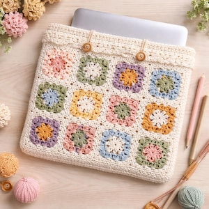 Puede incluir: Funda de ganchillo color crema para portátil con un diseño de patchwork colorido. Los cuadrados presentan colores pastel como rosa, amarillo y azul, y se aseguran con dos botones de madera. La funda está diseñada para un portátil.