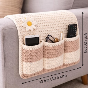 Puede incluir: Organizador de brazo de sofá tejido a ganchillo, 30,5 cm de ancho y 20,3 cm de alto. Cuenta con tres bolsillos a rayas crema y beige, una aplicación de margarita y espacio para teléfono, gafas, bolígrafo y mando a distancia.