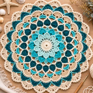 Puede incluir: Un tapete redondo hecho a mano con ganchillo en tonos crema, turquesa y azul claro. El tapete presenta un diseño floral central rodeado de anillos concéntricos de patrones intrincados. Los bordes son festoneados y el tapete está colocado sobre una superficie de madera.