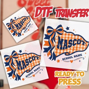 May include: A DTF transfer sheet featuring a pennant design with an orange and white gingham pattern, a large blue bow, and the text MASCOT and SCHOOL NAME. The graphic includes small star and heart accents on a white grid background.