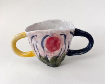 Taza de espresso de cerámica con dos asas y diseño de sol, ideal como regalo para amigos.