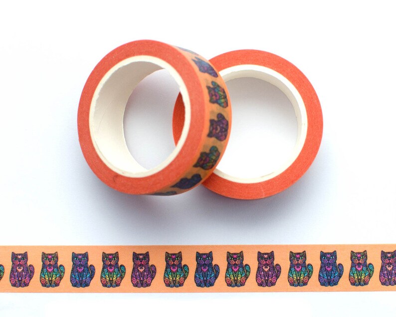 May include: Two rolls of orange washi tape with a repeating pattern of colorful, detailed sugar skull cats. The tape is unrolled to show the pattern.