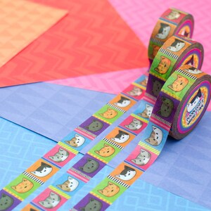 May include: Colorful washi tape rolls with a repeating pattern of cartoon cats' faces. The tape is unrolled on a blue background and shows the pattern of the tape.