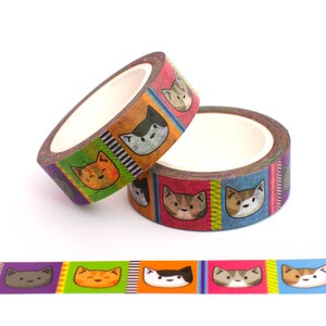 May include: Two rolls of colorful washi tape with a repeating pattern of cartoon cats. The tape is red, orange, yellow, green, blue, and purple. The cats are different colors and have different expressions.