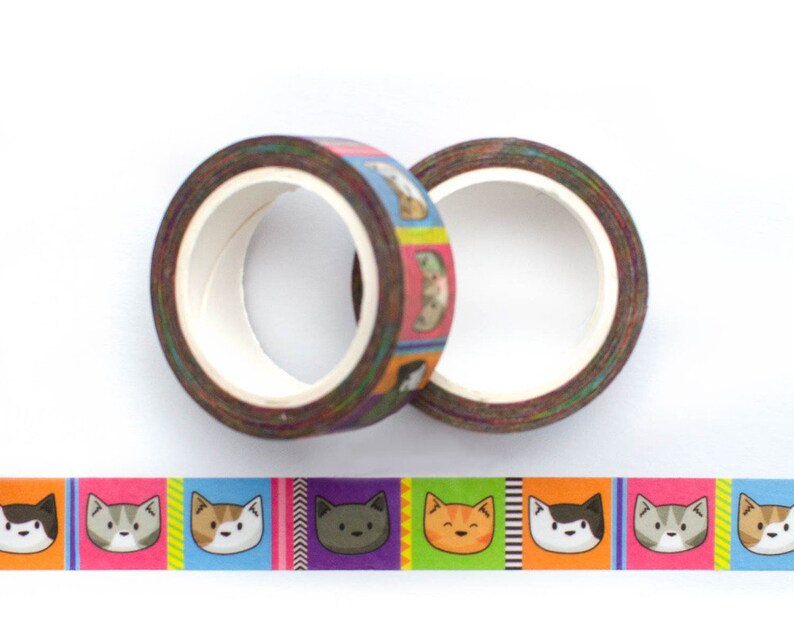 May include: Two rolls of colorful washi tape with a repeating pattern of cartoon cats. The tape is brown with a rainbow colored background and features different colored cats with different expressions.