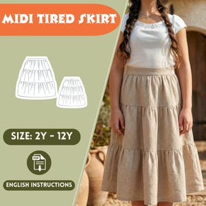 May include: A beige midi tiered skirt is shown, with a matching illustration of the skirt design. The text "MIDI TIRED SKIRT" is at the top, with "SIZE: 2Y - 12Y" and "ENGLISH INSTRUCTIONS" below. The skirt is worn by a person.