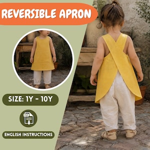 Può includere: Un grembiule reversibile giallo senape con design a schiena incrociata, indossato sopra pantaloni chiari. L'immagine include il testo REVERSIBLE APRON, SIZE: 1Y - 10Y e ENGLISH INSTRUCTIONS, con un'icona PDF e un inserto circolare frontale.