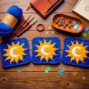 May include: Three square crochet motifs featuring a yellow sun and white crescent moon on a blue background, accompanied by a ball of blue yarn labeled Ethereal Stitches, three wooden crochet hooks, a wooden ring, gold beads, and star sequins.