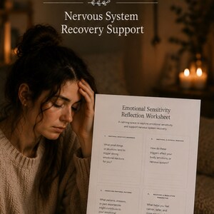 May include: A woman holds her head while looking at a worksheet titled "Emotional Sensitivity Reflection Worksheet." The worksheet is part of a "Nervous System Recovery Support" program. A cup of coffee and a lit candle are on the table.