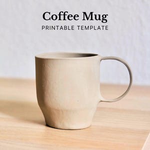 Könnte beinhalten: Eine beige Kaffeetasse mit rundem Henkel steht auf einer Holzoberfläche. Die Tasse hat eine zylindrische Form mit leicht konischem Boden. Über der Tasse steht der Text "Coffee Mug PRINTABLE TEMPLATE."