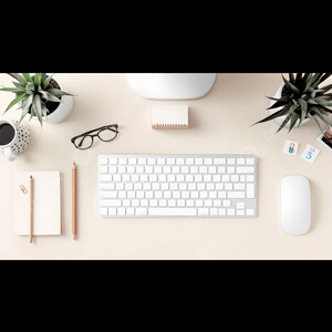 May include: Overhead shot of a minimalist workspace with a white keyboard, mouse, and notepad. A pair of black glasses, pencils, and a coffee cup are also present. Two small potted plants add a touch of greenery to the desk.