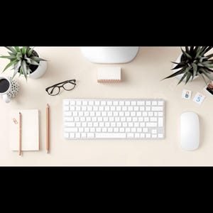 Peut inclure: Vue aérienne d'un espace de travail minimaliste avec un clavier, une souris et un bloc-notes blancs. Des lunettes noires, des crayons et une tasse à café sont également présents. Deux petites plantes en pot ajoutent une touche de verdure.