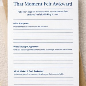 Könnte beinhalten: Ein weißes Papier mit dem Titel "That Moment Felt Awkward" mit Aufforderungen zur Reflexion. Die Seite enthält Abschnitte zur Beschreibung der Situation, der Gedanken und der Gefühle. Das Papier liegt auf einem Stapel neutralfarbenen Papiers mit goldenen Büroklammern.