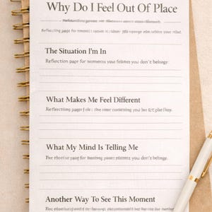 Könnte beinhalten: Ein Spiralbuch mit braunem Einband und linierten Seiten. Die oberste Seite trägt den Titel "Why Do I Feel Out Of Place" und enthält Aufforderungen zur Reflexion. Ein weißer und goldener Stift liegt auf dem Notizbuch.