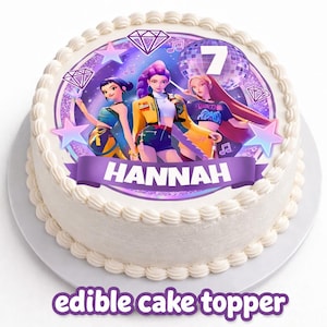 May include: A round white cake with an edible cake topper. The topper features three animated figures, a disco ball, musical notes, and the number 7. A purple banner displays the name "HANNAH". The words "edible cake topper" are at the bottom.