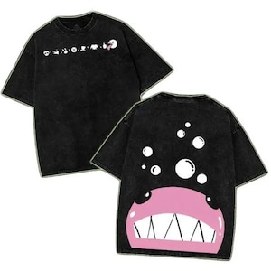 May include: A black acid-wash t-shirt featuring a row of small white icons on the chest and a large graphic on the back depicting a pink creature with sharp teeth and white bubbles floating above it against the dark fabric background.