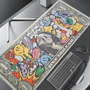 May include: A rectangular desk mat featuring a stylized one-dollar bill design with colorful graffiti-style illustrations. The graphic includes a central portrait of George Washington with a bandage, the text "MO MONEY", and various cartoon faces.