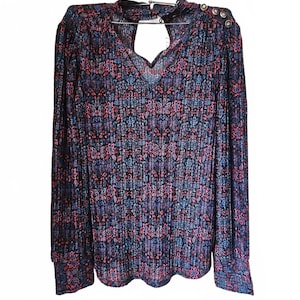 May include: A long-sleeved blouse with a floral pattern in shades of blue, pink, and purple. The blouse has a keyhole neckline and decorative buttons on the shoulder. The fabric appears to be pleated.