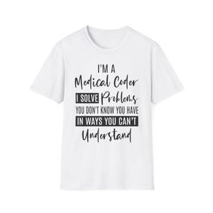 Op de afbeelding: Wit T-shirt met de zwarte tekst: "I'M A Medical Coder I SOLVE Problems YOU DON'T KNOW YOU HAVE IN WAYS YOU CAN'T Understand". Het shirt heeft een ronde hals en korte mouwen. De tekst is in een mix van lettertypen.