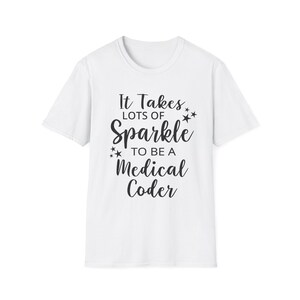Puede incluir: Camiseta blanca con el texto negro "It Takes Lots of Sparkle to Be a Medical Coder". El diseño incluye estrellas. La camiseta tiene mangas cortas y cuello redondo.