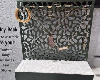 May include: A dark green jewelry rack with a decorative floral pattern, holding various necklaces and earrings. The rack has a white textured base and the text "Jewelry Rack" is visible.