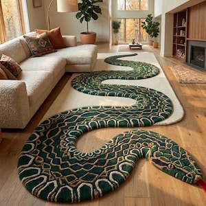 May include: A striking green and gold snake-shaped rug with a cream border, laid on a wooden floor. The rug's head has red detailing for the tongue and eyes. The rug is a unique decorative item for a living room.
