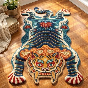 May include: A tufted area rug shaped like a stylised tiger, featuring a vibrant colour palette of deep blue, golden yellow, cream, and red. The design includes intricate patterns, a fierce facial expression, and a long tail, creating a bold floor accent.