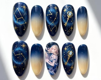 May include: A set of ten press-on nails featuring a dark blue to cream gradient. Some nails display gold constellations, others show gold ornate keys, and one nail features an illustration of a blonde anime character in a blue and white outfit.