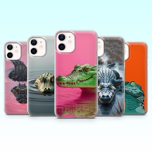 Peut inclure: Plusieurs coques de téléphone avec des motifs d'alligators. Les coques présentent des images en gros plan d'alligators dans divers environnements, avec des couleurs vives et des textures détaillées. Les coques sont roses, grises et oranges.
