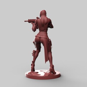 May include: A maroon-colored figurine of a female character in a combat outfit, holding a rifle. The figure is standing on a circular base. The character is wearing a fitted top, pants, and boots.