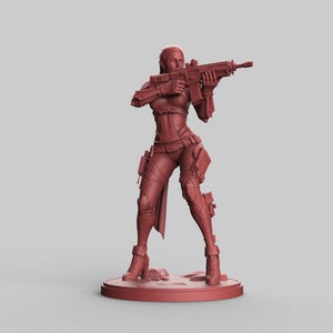 May include: A maroon-colored figurine of a female character in a combat pose, holding a rifle. The figure is wearing a detailed tactical outfit with pouches and knee pads. The figurine is standing on a circular base.