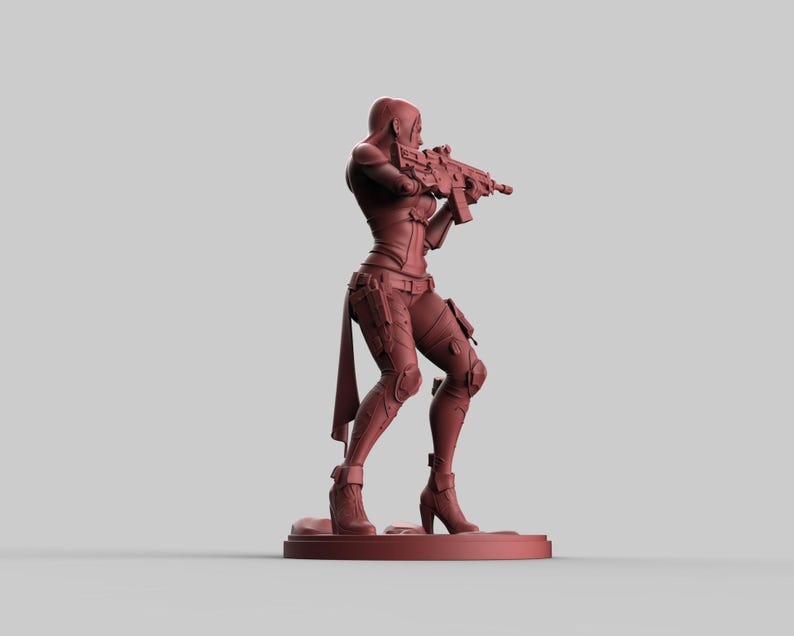May include: A reddish-brown figurine of a female character in a combat pose, holding a rifle. The figure is wearing a form-fitting outfit with knee pads and boots. The figurine is standing on a small, circular base.