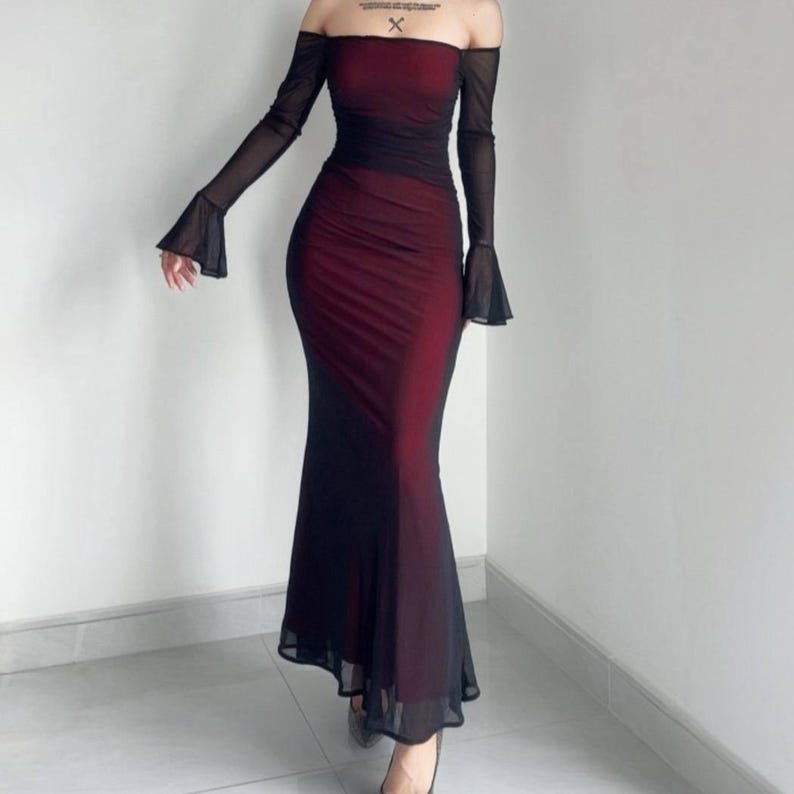 May include: A floor-length off-the-shoulder dress featuring a deep red base layer covered by a sheer black mesh overlay. The garment includes long, flared sleeves and a fitted bodice that transitions into a flowing, floor-length skirt.