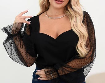 May include: Black top with a sweetheart neckline and sheer, polka-dot sleeves. The top has a fitted bodice and long sleeves with ruffled cuffs. The model is wearing dark blue jeans and a silver necklace.