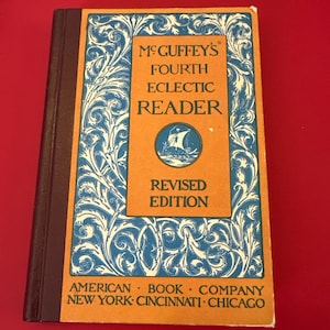 May include: A vintage book titled "McGuffey's Fourth Eclectic Reader, Revised Edition." The cover is orange with blue and white decorative scrollwork. The book's spine is brown, and the text "American Book Company, New York, Cincinnati, Chicago" is at the bottom.
