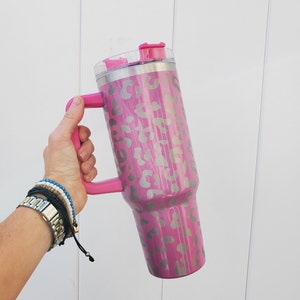 May include: A pink stainless steel tumbler with a leopard print design and a pink lid and handle.