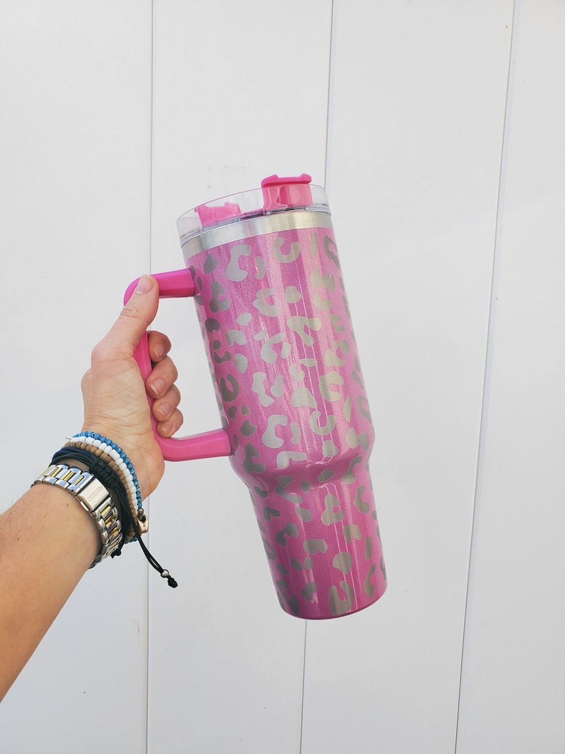 May include: A pink stainless steel tumbler with a leopard print design and a pink lid and handle.