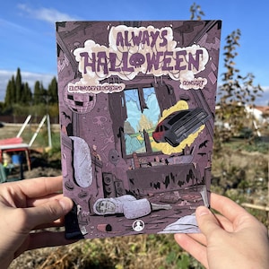 May include: A comic book cover with the title "Always Halloween" in purple and white. The artwork depicts a spooky interior scene with a broken window, a car, and a figure lying on the floor. The background is a blue sky.