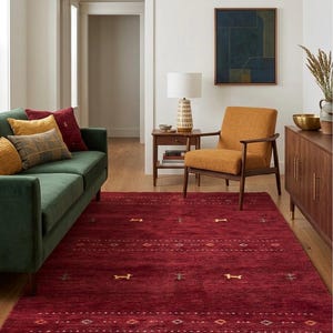 Peut inclure: Un tapis rouge foncé avec un motif géométrique dans un salon. Le tapis présente une surface texturée et est placé devant un canapé vert et une chaise orange. La pièce a un parquet et des murs neutres. Dimensions: environ 240 x 300 cm.