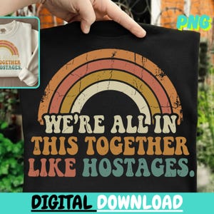 May include: Black sweatshirt with a retro rainbow design and the text "WE'RE ALL IN THIS TOGETHER LIKE HOSTAGES." A smaller image of a cream-colored sweatshirt with a rainbow design is in the upper left corner. The words "DIGITAL DOWNLOAD" are at the bottom.