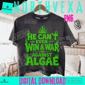 Könnte beinhalten: Ein anthrazitfarbenes Kurzarm-T-Shirt mit hellgrünem Text, der HE CAN'T EVEN WIN A WAR AGAINST ALGAE lautet. Das Design enthält stilisierte grüne Algenillustrationen, die den fetten Text in Blockbuchstaben auf der Vorderseite umgeben.