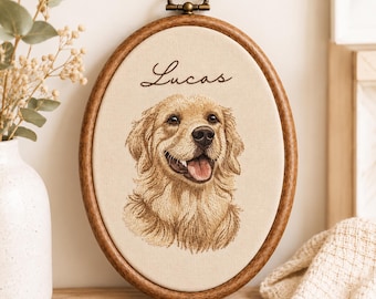 May include: An oval wooden embroidery hoop frame containing a beige fabric panel with a detailed thread-stitched portrait of a golden retriever dog and the name Lucas embroidered in dark brown script lettering above the dog.