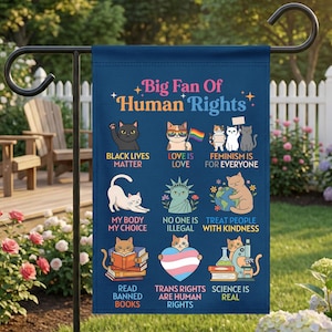 May include: A navy blue garden flag with the text "Big Fan Of Human Rights" and illustrations of cats with various slogans, including "Black Lives Matter," "Love is Love," and "Trans Rights are Human Rights."