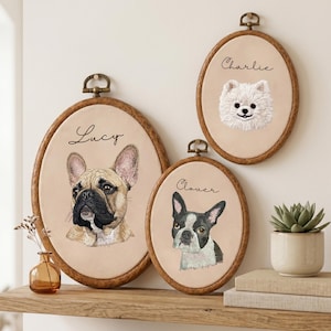 May include: Three oval wooden embroidery hoops containing fabric portraits of dogs. The largest hoop features a French Bulldog labeled Lucy, the medium hoop a Boston Terrier labeled Clover, and the smallest hoop a white Pomeranian labeled Charlie.