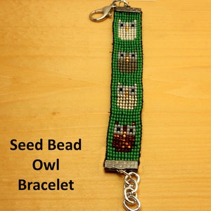 May include: A green seed bead bracelet with four owl designs. The bracelet has a silver clasp and a silver chain.