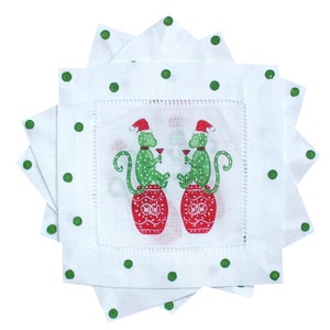 May include: Set of four white linen napkins with green polka dots and a red and green Christmas monkey design. The monkeys are wearing Santa hats and holding glasses of wine.