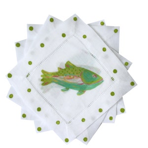 May include: Set of four white linen napkins with green polka dots and a green and blue fish illustration in the center.