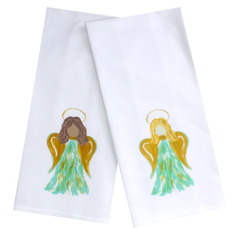 Puede incluir: Dos toallas de cocina blancas con un dise&ntilde;o de &aacute;ngel pintado. Un &aacute;ngel tiene el pelo casta&ntilde;o y el otro tiene el pelo rubio. Ambos &aacute;ngeles tienen alas doradas y un halo.